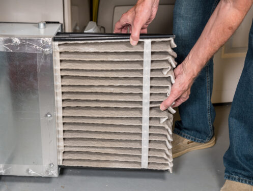 A man changing a dirty furnace air filter in Foothill Ranch, CA